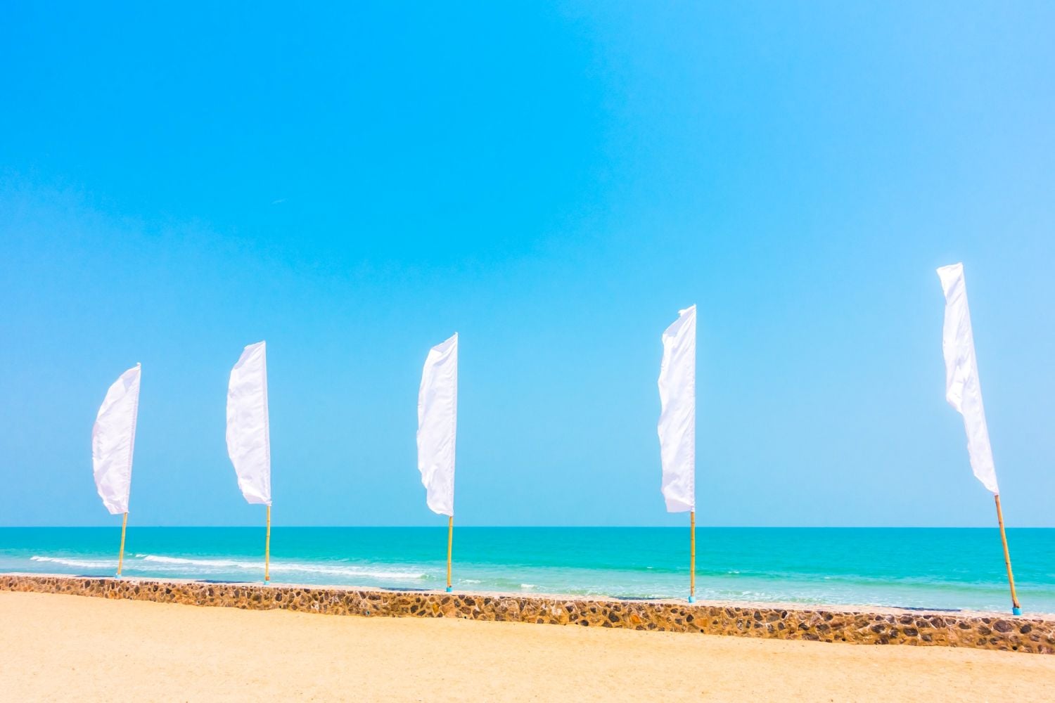 Białe flagi na plaży nad morzem na tle morza